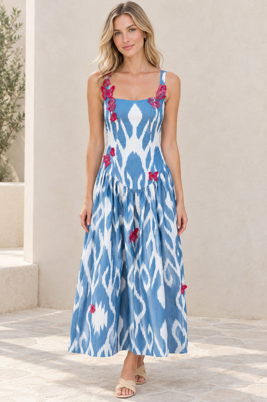 Front view of model wearing blue and white ikat print square neck maxi dress with pink butterfly appliques