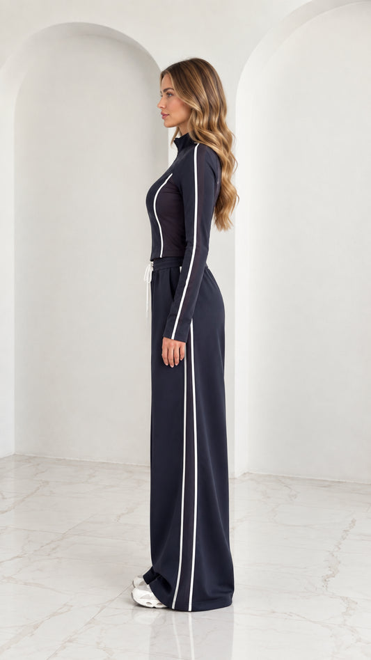Side profile view of model wearing Navy Blue tracksuit set with vertical white stripe detail