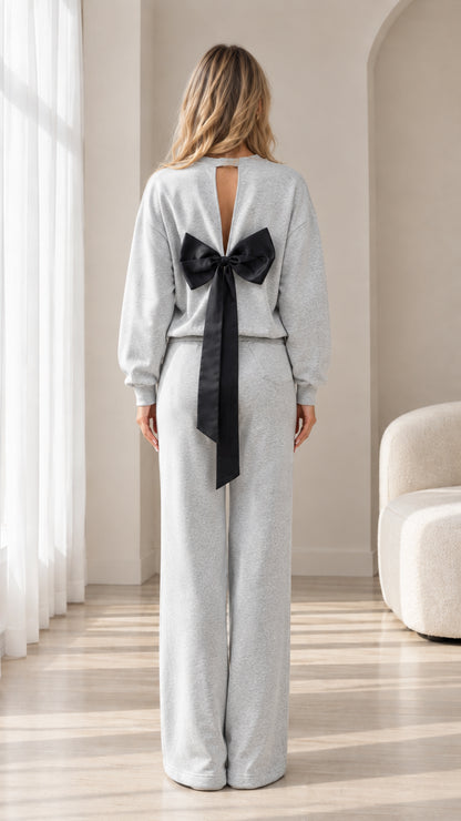 Back view of model showing crewneck top with keyhole cut-out and large black bow detail