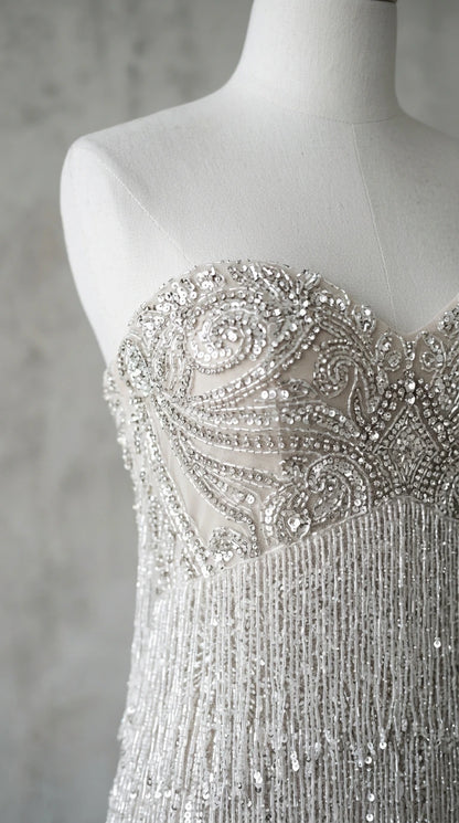 Close-up of intricate beaded scrollwork and fringe detail on dress bodice