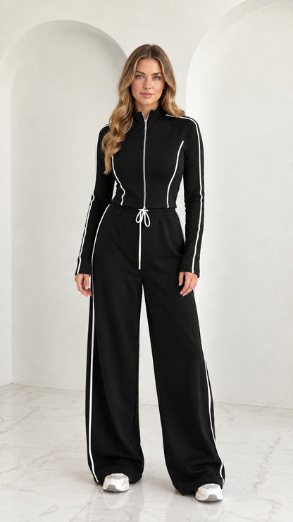 Full front view of model wearing Black 2-piece zip-up tracksuit set with white piping