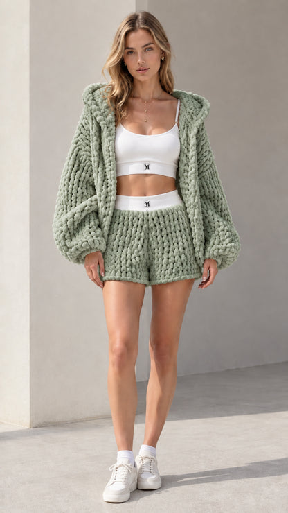 Model wearing sage green chunky knit hooded cardigan and matching shorts set